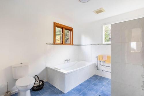 a white bathroom with a tub and a toilet at Sea views from holiday home in Lower Hutt
