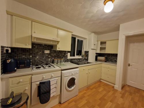 a kitchen with white cabinets and a washer at Swanley Guest House in Kent