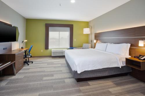 a hotel room with a bed and a flat screen tv at Holiday Inn Express Hotel and Suites Katy by IHG in Katy