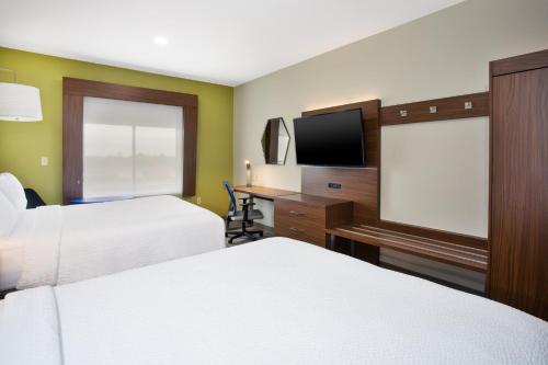 a hotel room with two beds and a flat screen tv at Holiday Inn Express Hotel and Suites Katy by IHG in Katy