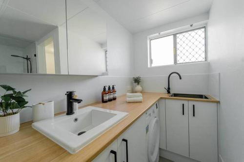 a white kitchen with a sink and a mirror at Quiet Family Apartment Near Beach with Pool in Gold Coast