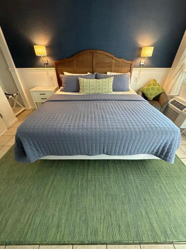 a bedroom with a large bed with a blue comforter at Boardwalk Beach Inn in Point Pleasant Beach