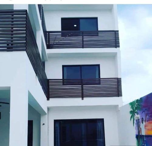 a white building with black balconies on the side of it at ALMAR FAMILY HOUSE in Holbox Island