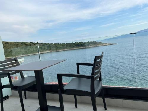 a table and chairs on a balcony overlooking the water at Villa Xhefri 2 in Sarandë