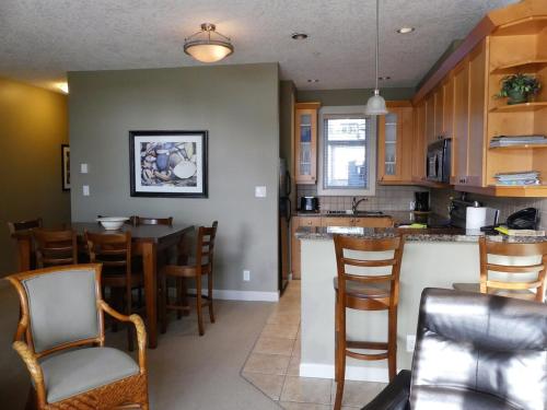 a kitchen with a bar and a dining room with chairs at Ocean View Townhome - Sooke Harbour Marina in Sooke