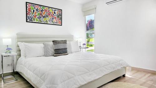 a white bedroom with a large bed and a window at El Cielo by Villa Alejandro in Boquete