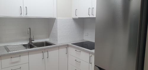 a kitchen with white cabinets and a stainless steel refrigerator at Beautiful, inner city, renovated top floor 2-bedroom apartment in Canberra