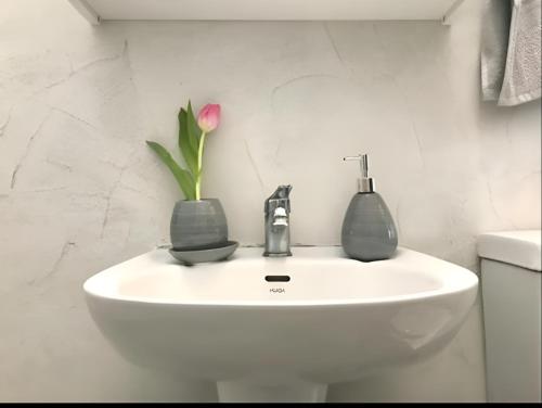 un lavabo con una flor en un jarrón. en Rising Sun House Santorini en Firostefani