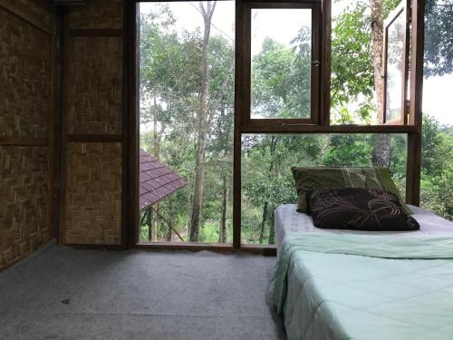 a bedroom with a bed and a large window at Joben Ecolodge in Tetebatu