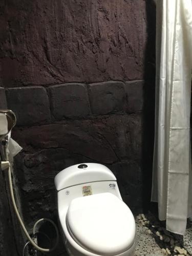 a white toilet in a bathroom with a brick wall at Joben Ecolodge in Tetebatu