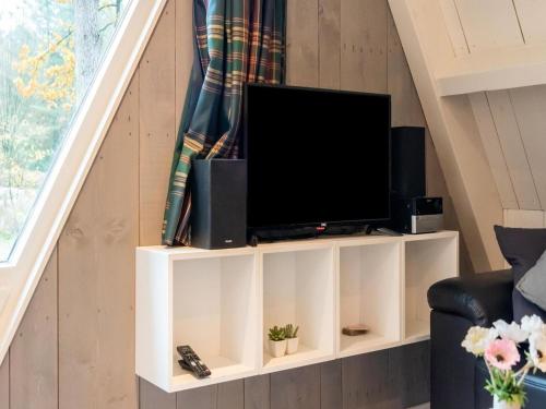 a living room with a tv on a white book shelf at Semi-detached bungalow 'Muizenoortje' at park Vosseven in Stramproy
