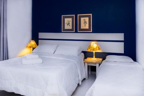 2 camas en un dormitorio con paredes azules y 2 lámparas en Villa Salvia Geriba Beach ao lado Fishbone, en Búzios