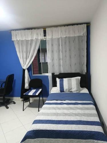 Dormitorio azul y blanco con cama y ventana en Apartamento cerca al estadio en Medellín 202-1, en Medellín