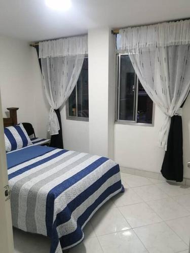1 dormitorio con cama de rayas azules y blancas y ventanas en Apartamento cerca al estadio en Medellín 202-1, en Medellín