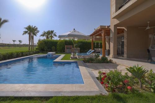 a swimming pool in a yard next to a house at Safty Palm Oasis Private Pool & Beach Access in Ain Sokhna