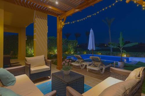 a patio with chairs and an umbrella at night at Safty Palm Oasis Private Pool & Beach Access in Ain Sokhna