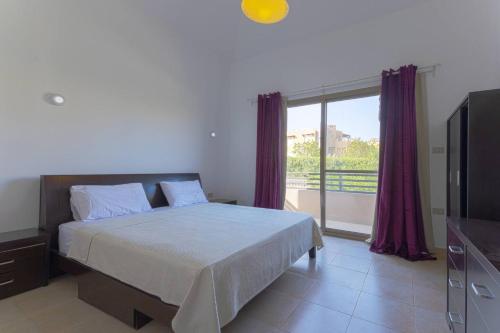 a bedroom with a bed and a large window at Safty Palm Oasis Private Pool & Beach Access in Ain Sokhna