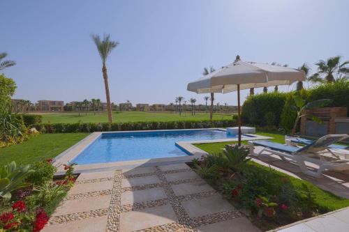 a swimming pool with an umbrella and two chairs and a table at Safty Palm Oasis Private Pool & Beach Access in Ain Sokhna