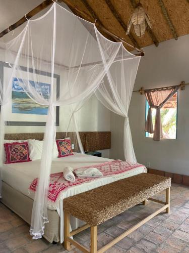a bedroom with a bed with a mosquito net at Vilarejo Macapá Chalés in Luis Correia