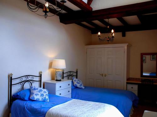 a bedroom with two beds with blue sheets and a mirror at Tranquil Cottage in Normandy in Sainte-Marguerite-dʼElle