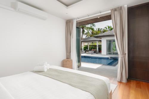 a bedroom with a large bed and a swimming pool at Tropical villa within 5 minutes walk to Bangtao Beach in Bang Tao Beach