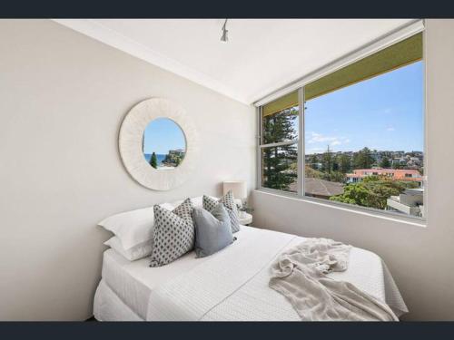 a white bedroom with a large window and a bed at SeaDreams Beachfront Manly in Manly 