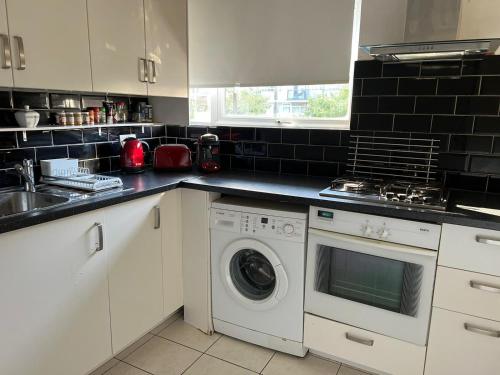 a kitchen with a washing machine and a sink at London City Apartment in London