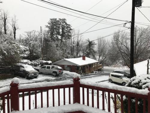 a snow covered yard with cars parked in front of a house at Mountain Aire Cottages, Inn, & Glamping in Clayton
