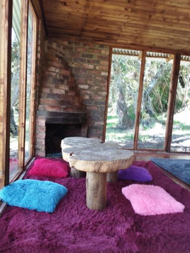 a wooden table sitting on a rug in a room with a fireplace at CABAÑAS ALASKA in Sesquilé