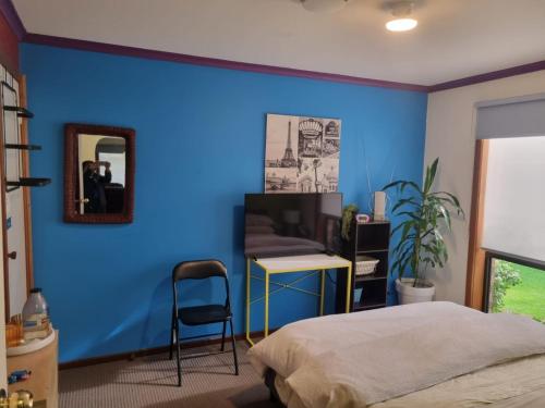 Tani Family home في Rowville: غرفة نوم بحائط ازرق مع سرير ومرآة