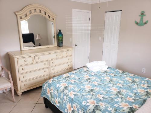 a bedroom with a dresser and a bed and a mirror at OCEAN VACATION BREEZE in Lantana