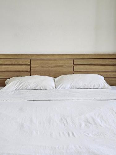 a bed with white sheets and a wooden headboard at Sawairiang Place in Nakhon Ratchasima