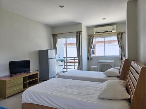 ein Hotelzimmer mit 2 Betten und einem TV in der Unterkunft Sawairiang Place in Nakhon Ratchasima