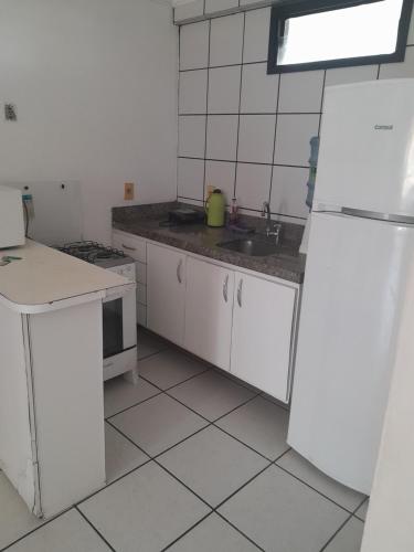 eine weiße Küche mit einer Spüle und einem Kühlschrank in der Unterkunft Residence Porto de Iracema in Fortaleza