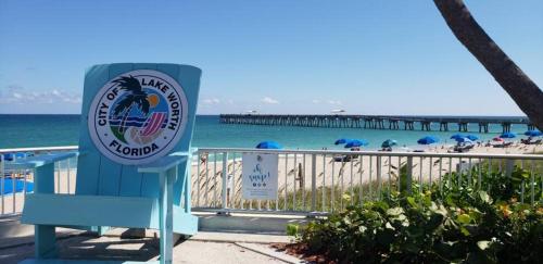 a sign at the beach with a pier in the background at OCEAN VACATION BREEZE in Lantana
