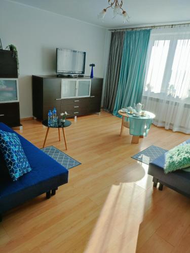 sala de estar con sofá azul y mesa en Apartament nad Nidą, en Sobków