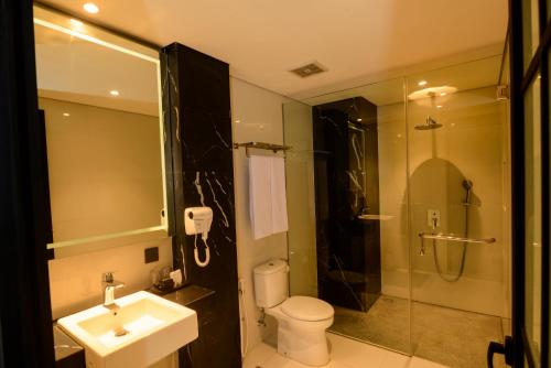 a bathroom with a toilet and a sink and a shower at Nata Azana Hotel Solo in Solo