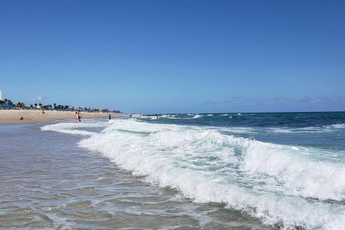 a beach with people walking in the water and waves at OCEAN VACATION BREEZE in Lantana