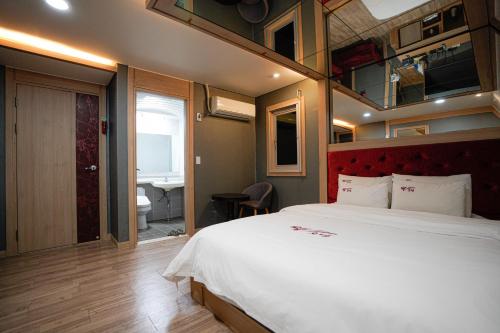 a bedroom with a large bed and a bathroom at Mokpo Well hotel in Mokpo