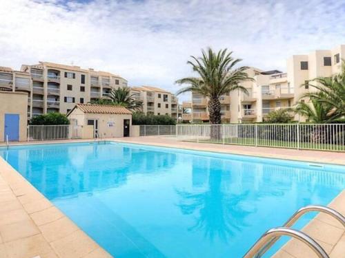une grande piscine bleue avec des bâtiments en arrière-plan dans l'établissement Studio en RDC avec Jardin Privatif et Piscine, à 50m de la Plage - Saint-Cyprien - FR-1-732-6, à Saint-Cyprien