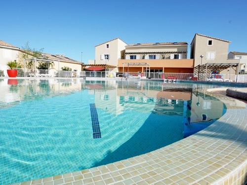 une grande piscine d'eau bleue en face des bâtiments dans l'établissement Pavillon T3 avec Piscine, Spa et Salle de Sport près de la Plage - 6 Couchages - FR-1-732-38, à Latour-Bas-Elne