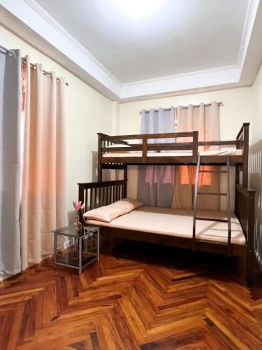 a room with two bunk beds and a wooden floor at Cozy Millenium House in Baguio