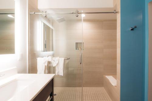 a bathroom with a shower and a sink and a toilet at The Cove Hotel in Long Beach