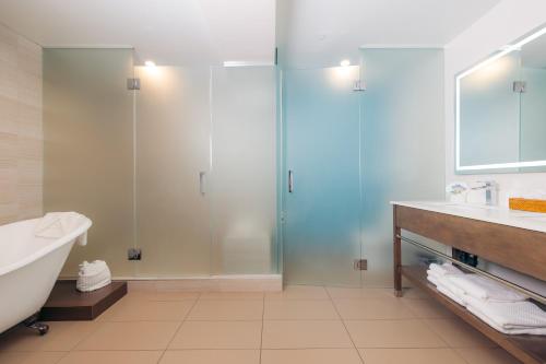 a bathroom with a shower and a tub and a sink at The Cove Hotel in Long Beach