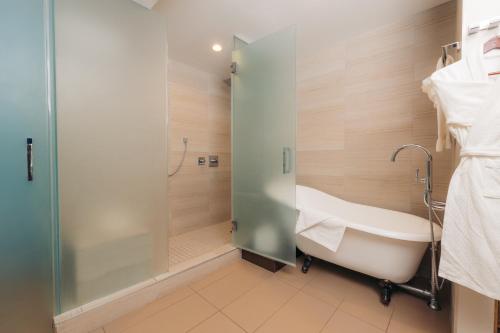 a bathroom with a tub and a glass shower at The Cove Hotel in Long Beach