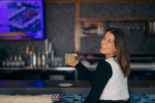 a woman holding a drink in a bar at The Cove Hotel in Long Beach