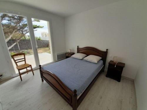 une chambre avec un lit, une chaise et une fenêtre dans l'établissement Villa T4 plain-pied proche plage, terrasse, parking, animaux acceptés - Saint-Gilles-Croix-de-Vie - FR-1-324-559, à Saint-Gilles-Croix-de-Vie