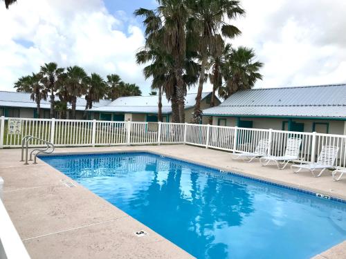 una piscina con sillas, una valla y palmeras en captain's quarters, en Port O'Connor