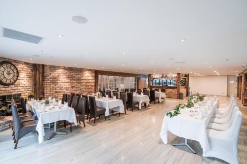 a dining room with white tables and black chairs at Northridge Golf Resort in Orewa