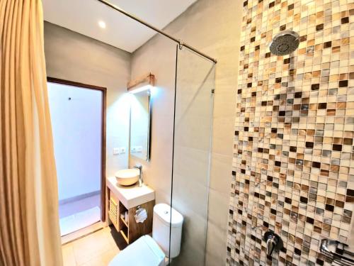 a bathroom with a toilet and a glass shower at Kamandaka in Kuta